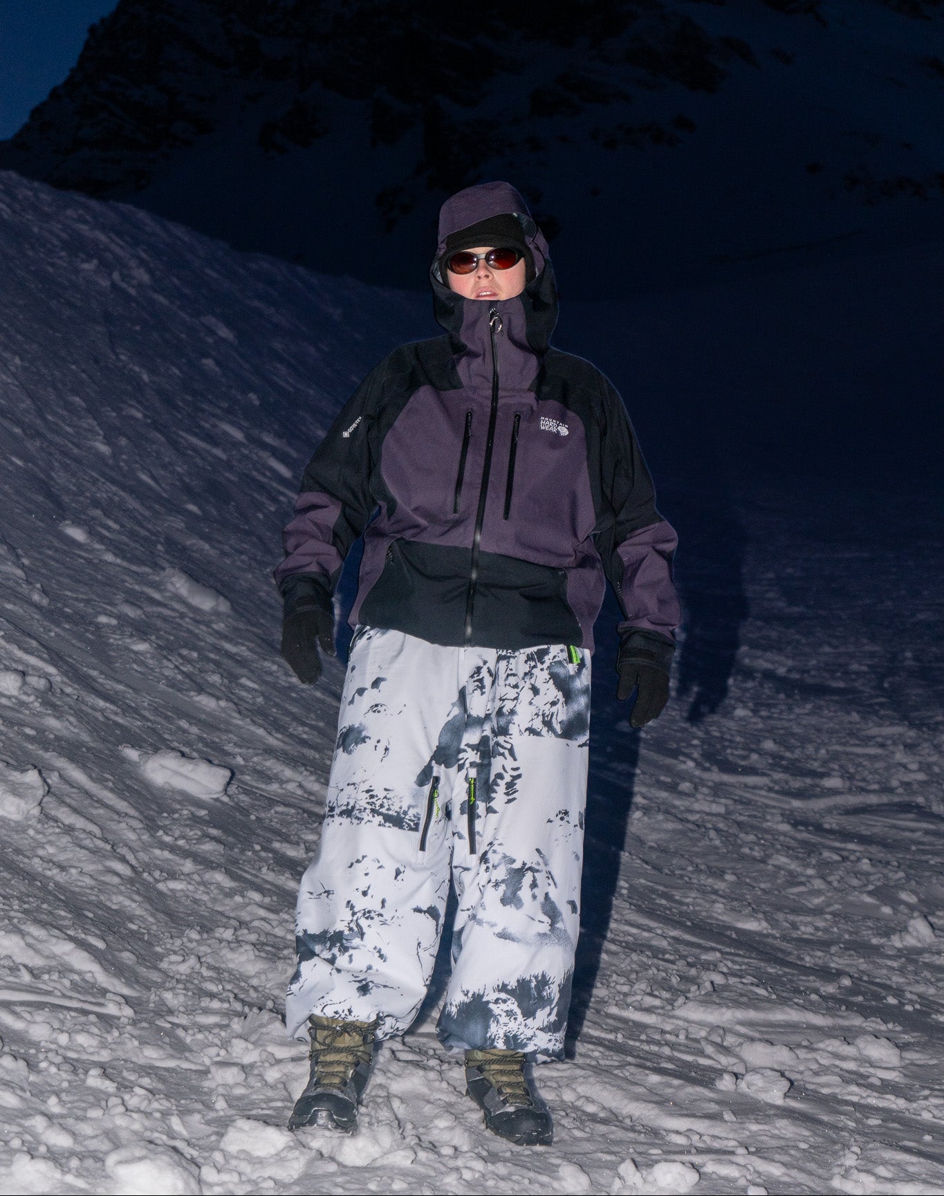 Person in winter clothing standing on a snowy mountain at night